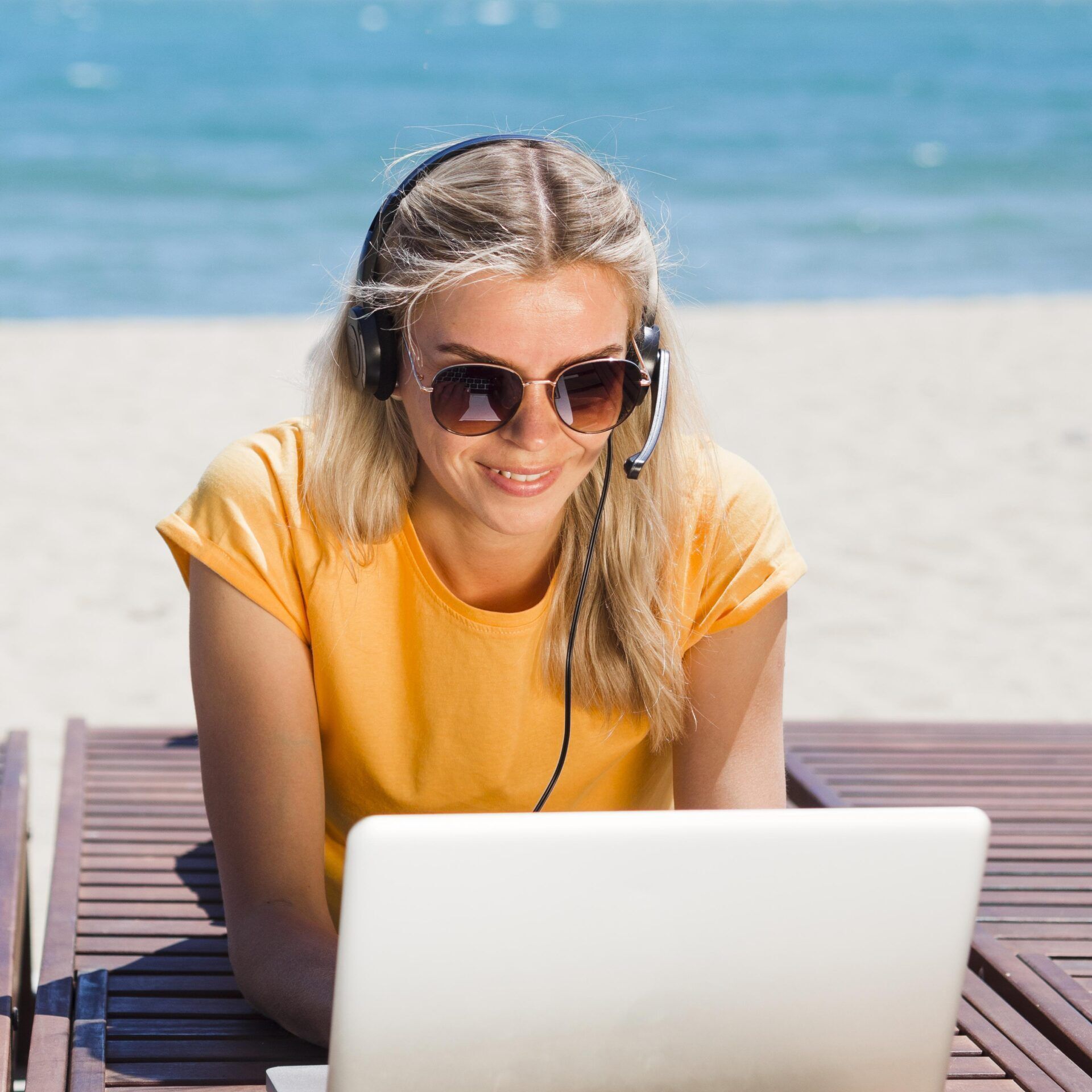 front-view-woman-with-headset-laptop-working-beach